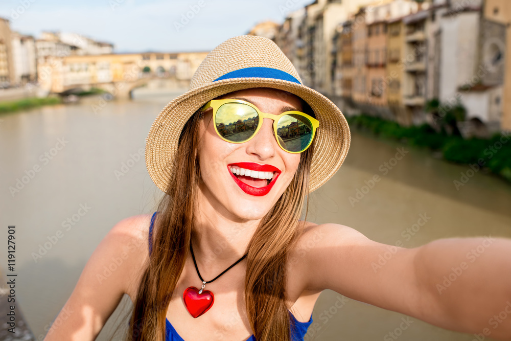 Young female traveler making selfie portrait in front of the famous bridge in Florence city in Italy