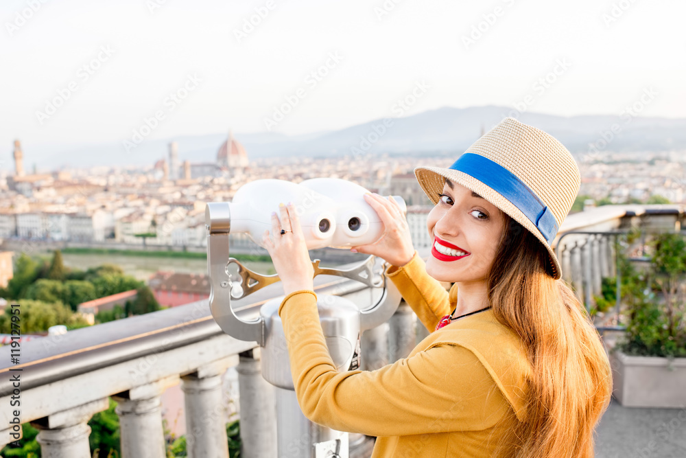 Young female tourist looking with telescope on the old town of Florence from Michelangelo square in 