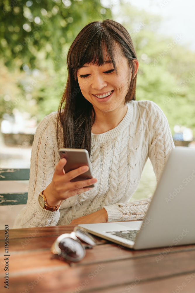 Smiling woman using cellphone at coffee shop