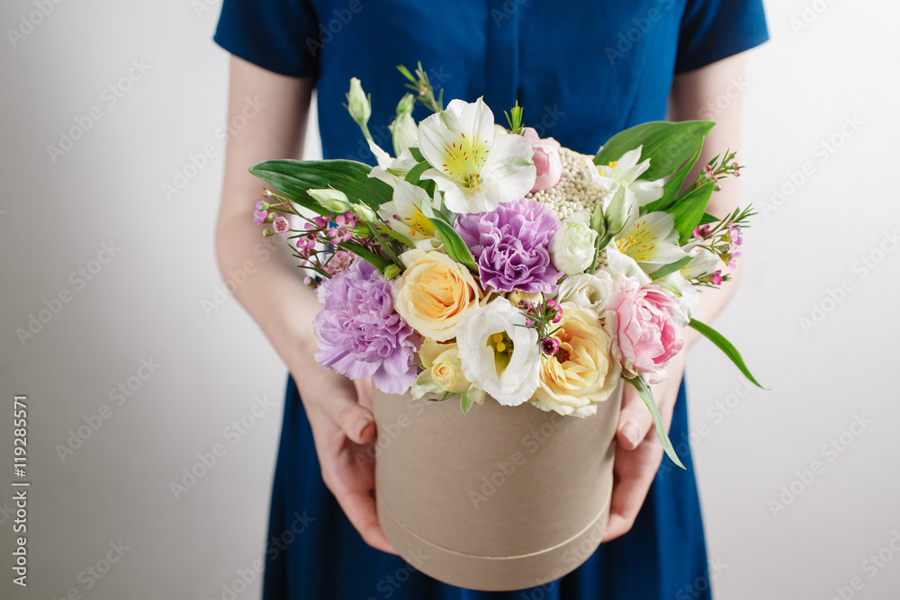 工作花店，在一个圆形盒子里花束。闻着花的味道，帽子里的桃玫瑰靠在塑料上