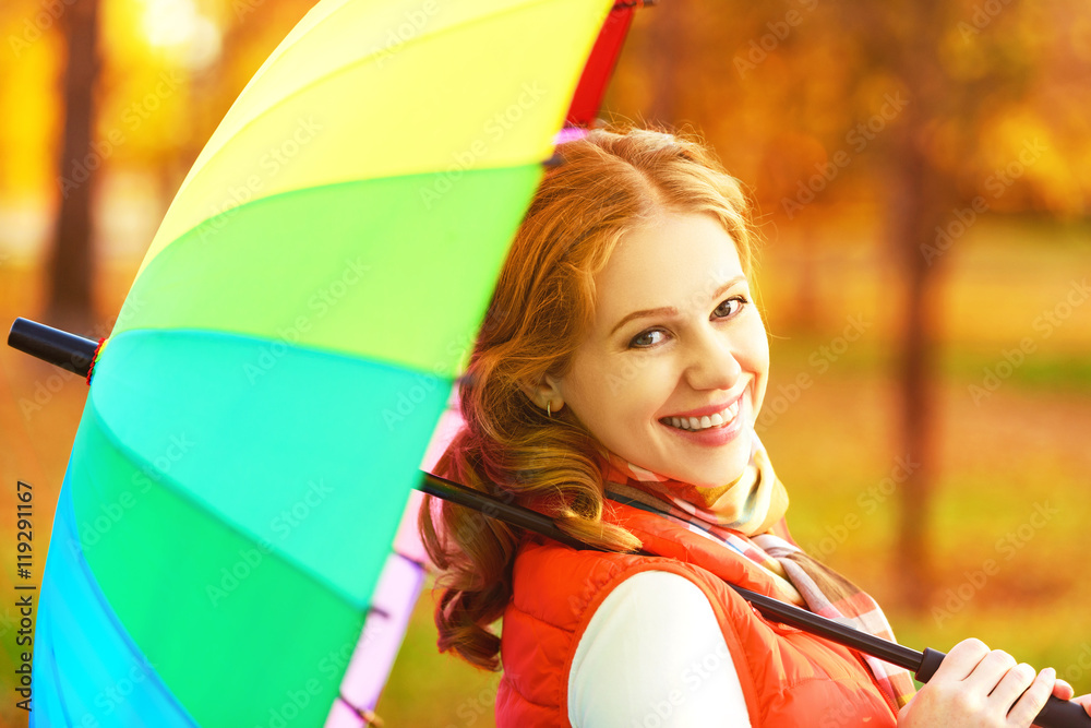 happy woman with rainbow multicolored umbrella under rain in par