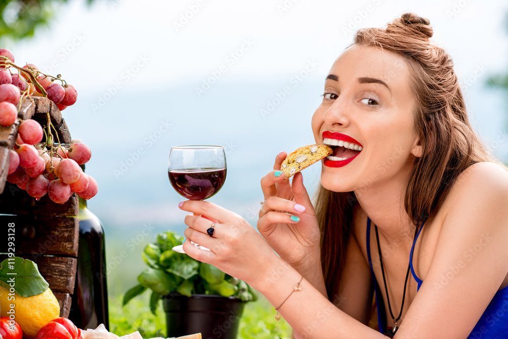 Beautiful woman tasting cantuccini cookie lying on the grass with lots of tasty italian food and win