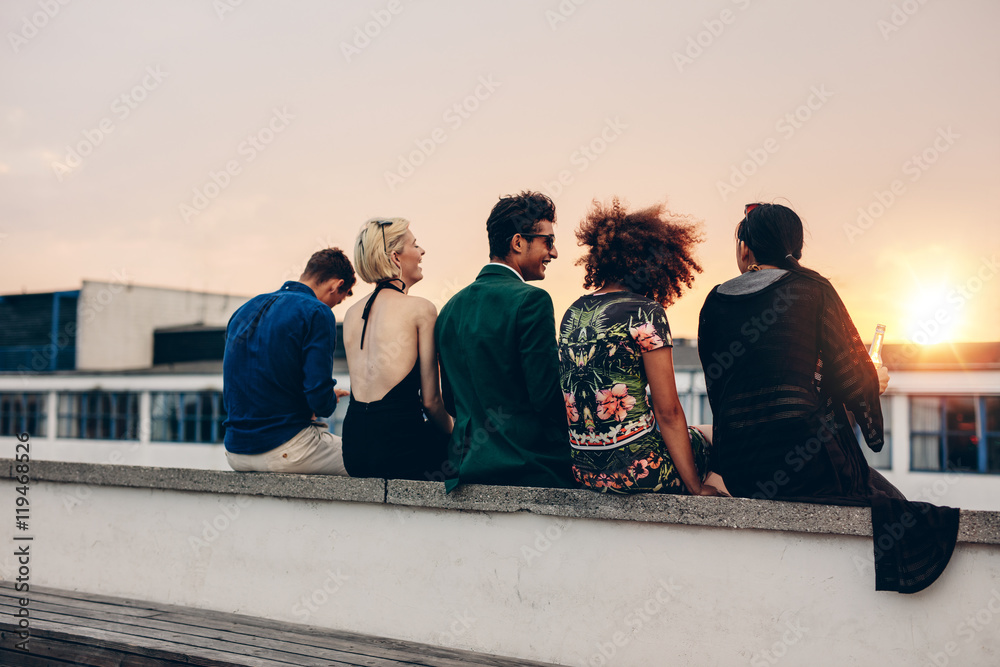 Young friends relaxing on terrace during sunset