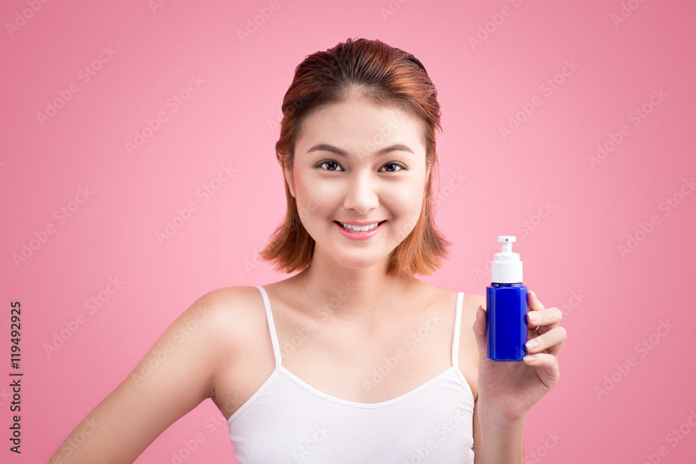 Woman use body lotion on arms and holding cosmetics bottle on pi