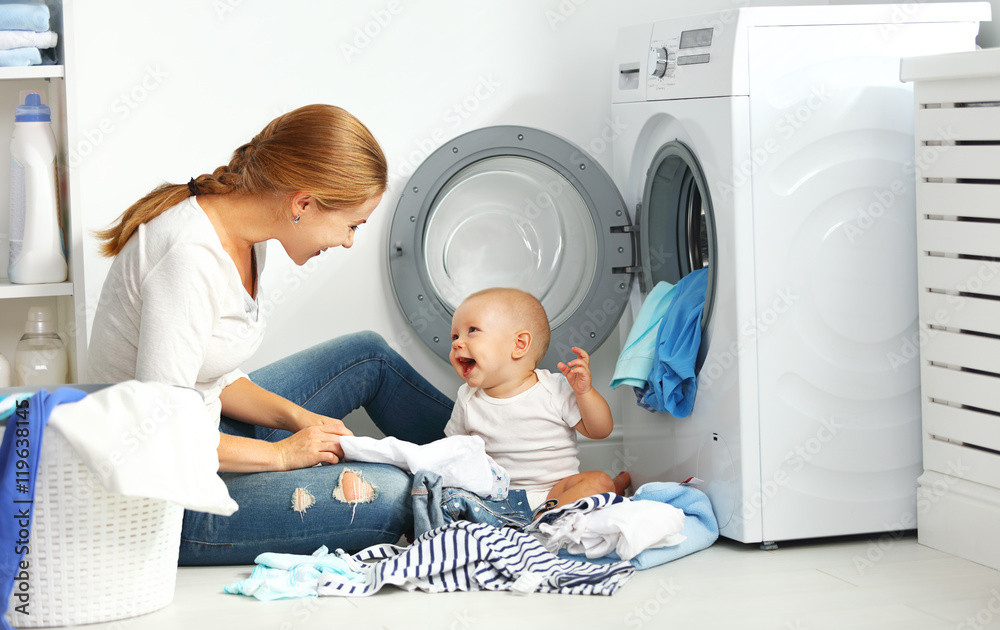 mother a housewife with a baby  fold clothes into the washing ma