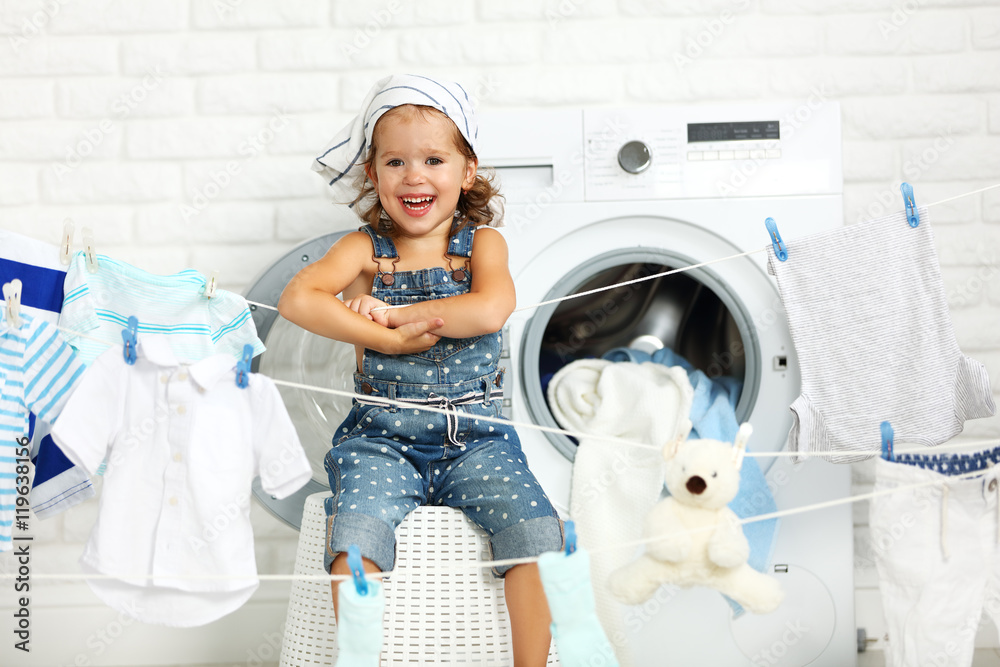 child fun happy little girl  to wash clothes and laughs in laund