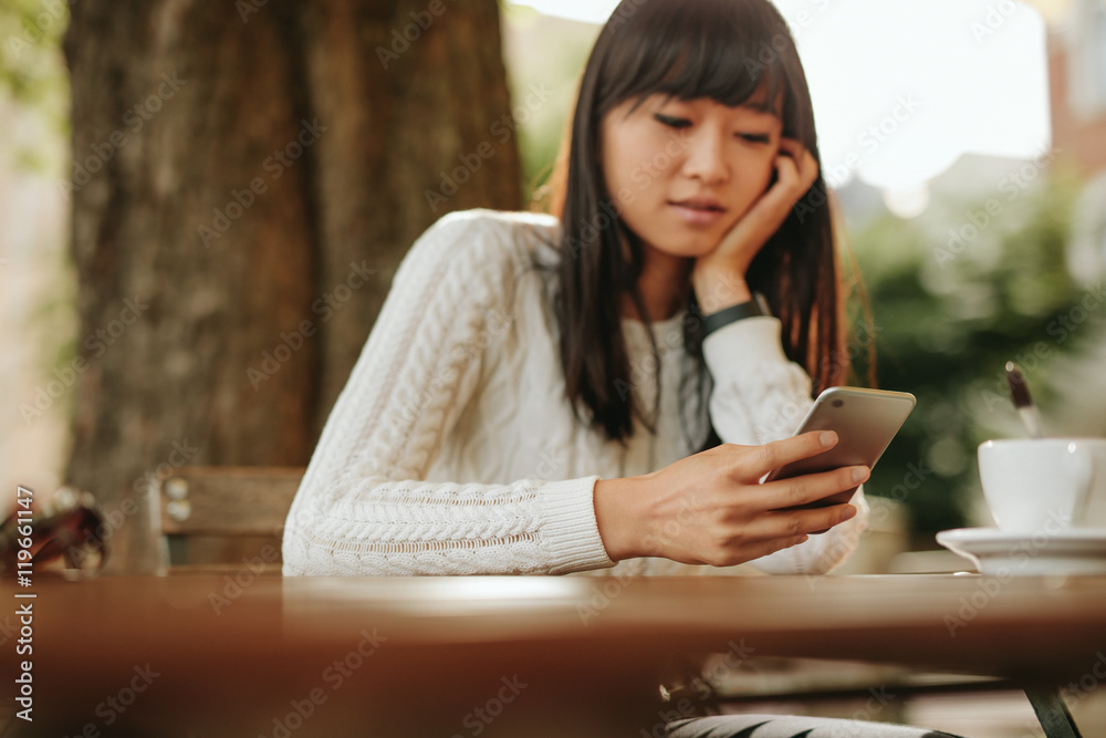 中国女人在户外咖啡馆拿着手机