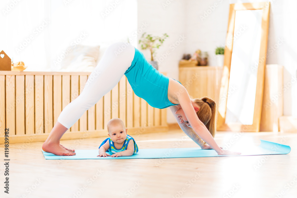 sports mother is engaged in fitness and yoga with baby at home