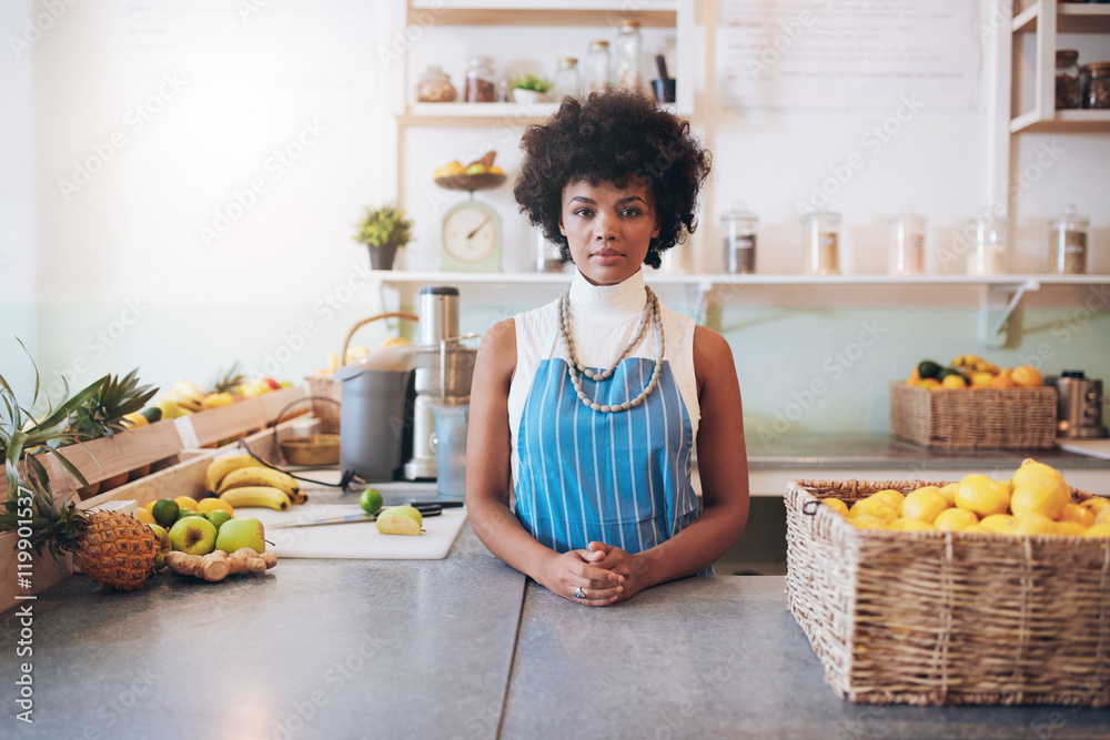 Young african woman behind juice bar counter