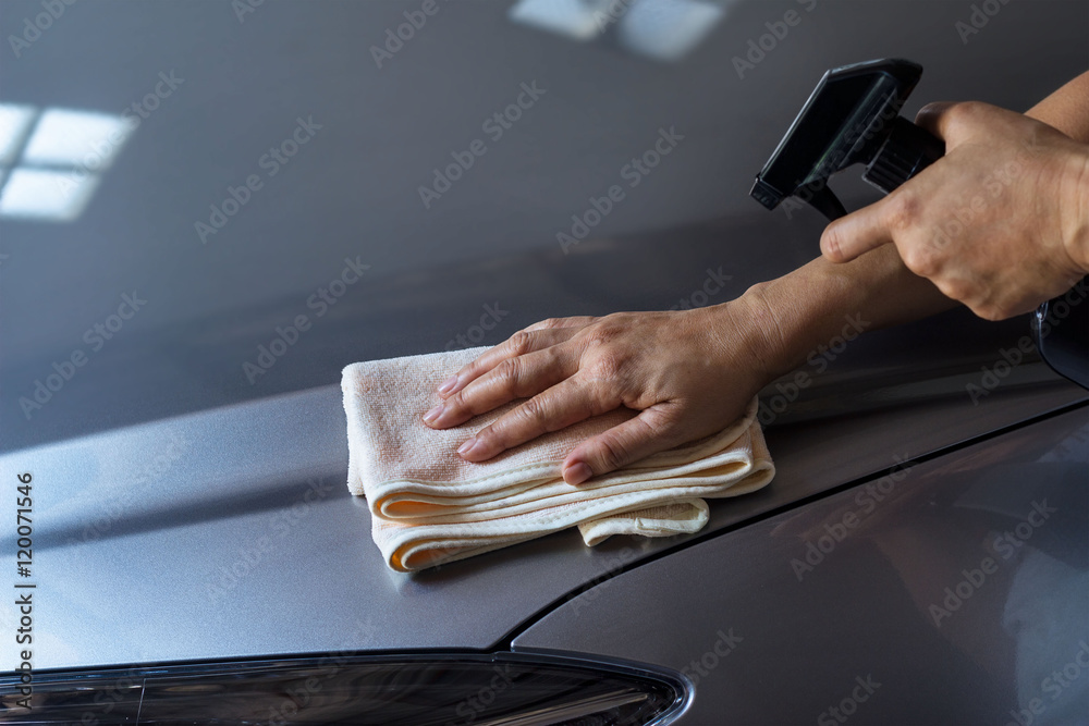 woman cleaning car with microfiber cloth and cleaning spray