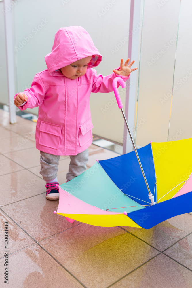 打着五颜六色雨伞的小女孩在雨中行走。