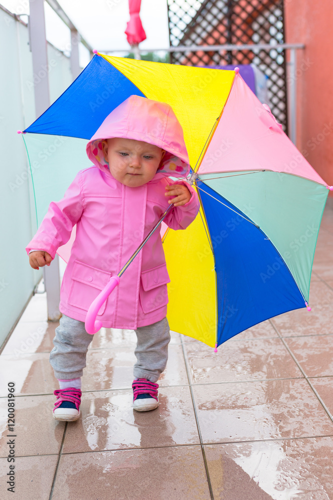 打着五颜六色雨伞的小女孩在雨中行走。