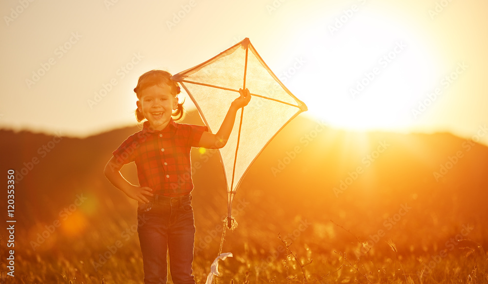 happy child girl with a kite on meadow in summer