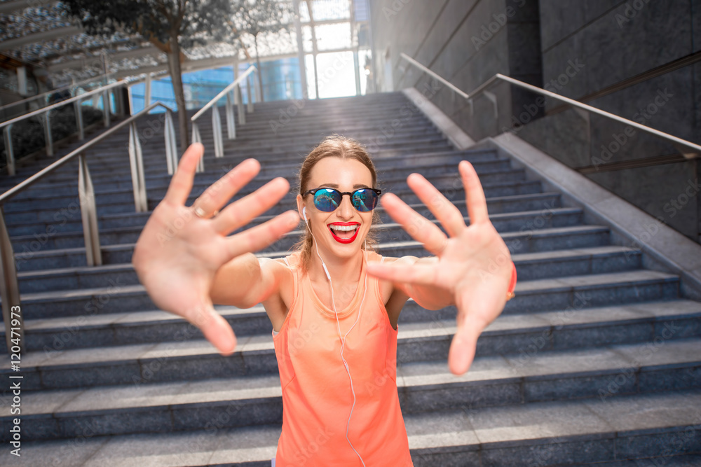 Joyful sports woman giving a five with hands before training in the modern city. Healthy lifestyle i