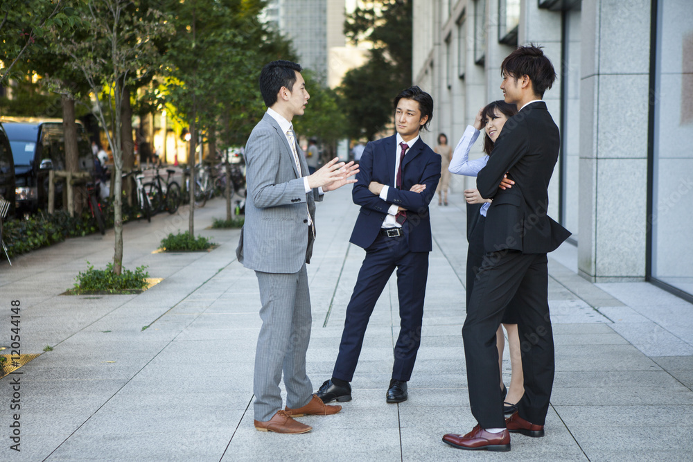 Four businessmen who are the stand talking in the office district