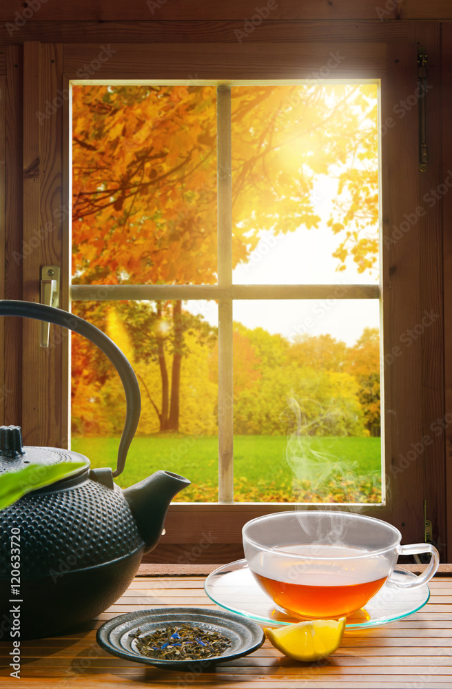 schwarzer Tee mit Zitrone im Herbst am Fenster einer Holzhütte