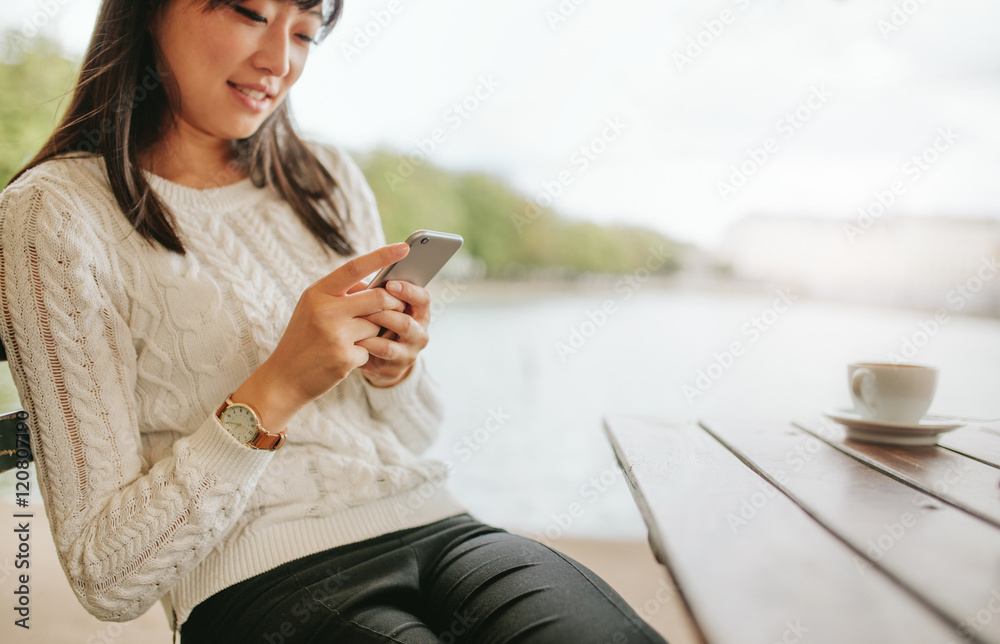 Attractive young female using cellphone at cafe