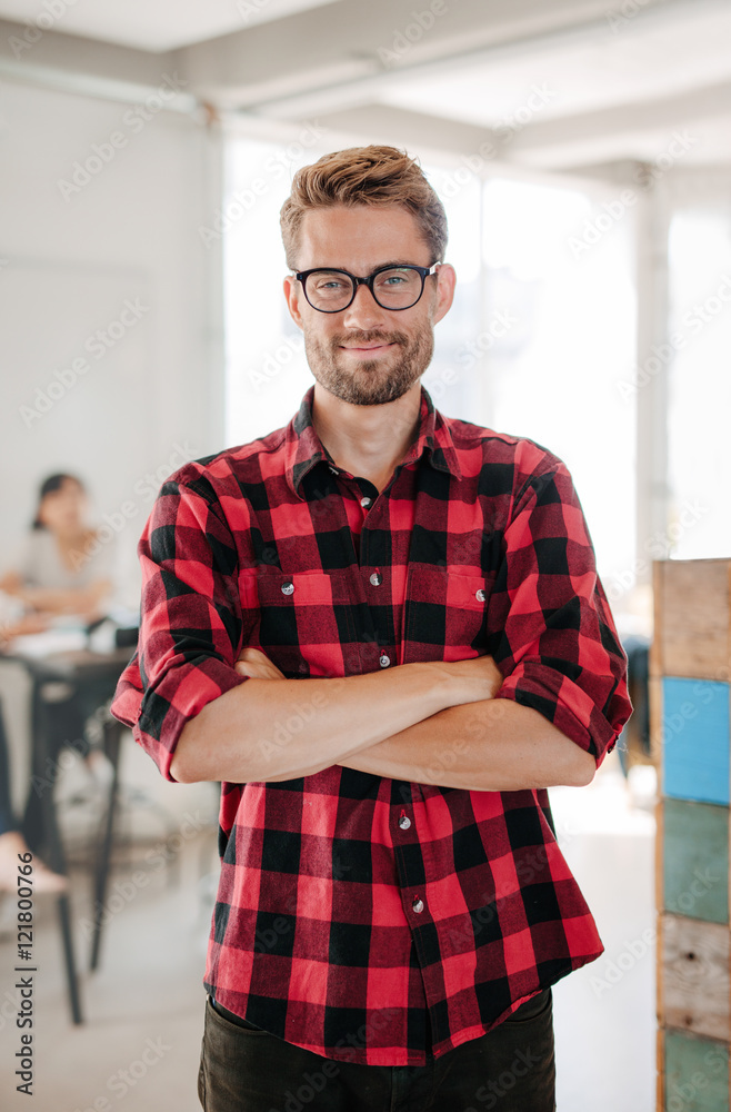 Happy young startup owner standing in office