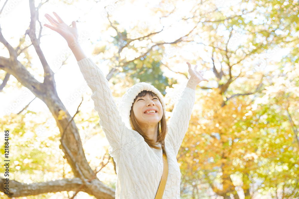 手を広げる女性　紅葉背景