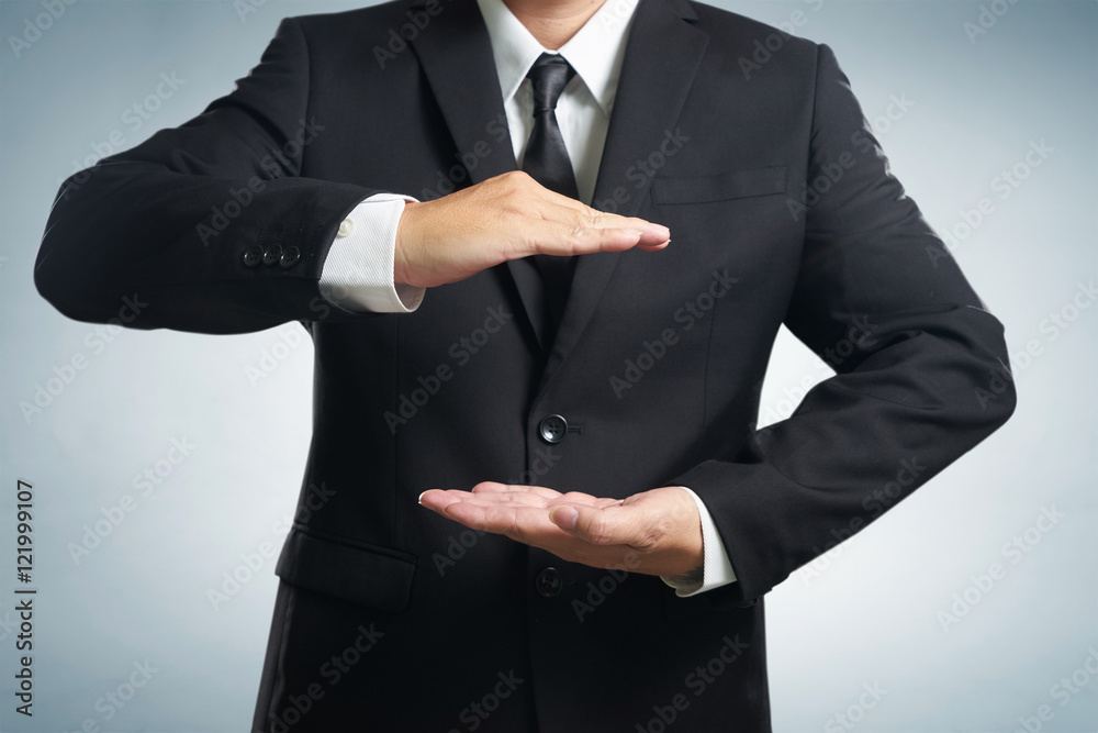 Businessman in suit with two hands in position to protect something (focus on hand, blur out the sui