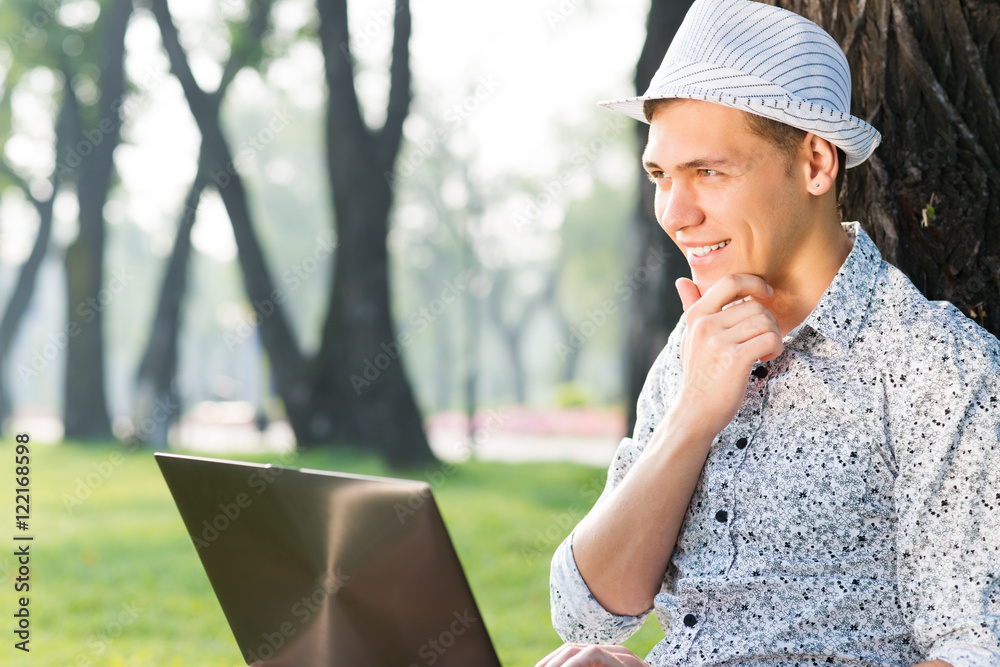 young man working in the park with a laptop