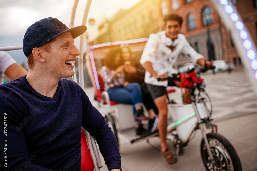 Happy young man enjoying tricycle ride with friends