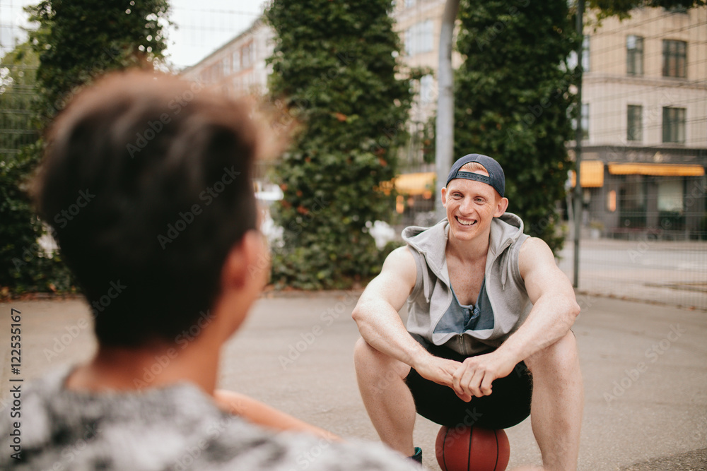 Two friends relaxing after playing basketball on court