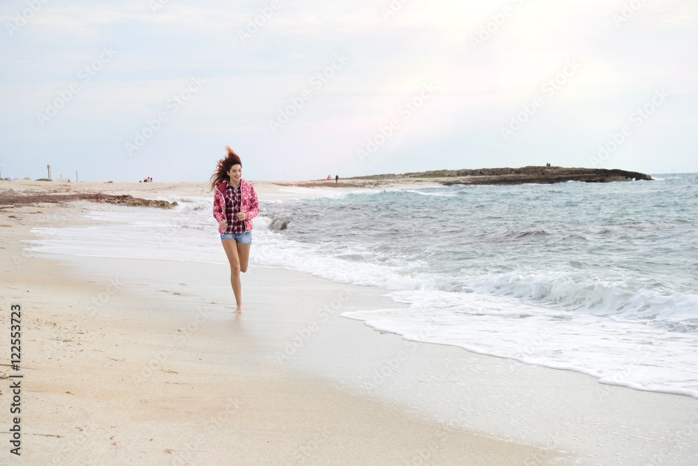 beautiful girl with colorful windbreaker running on the beach