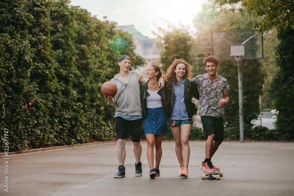 Happy teenage friends enjoying on basketball court