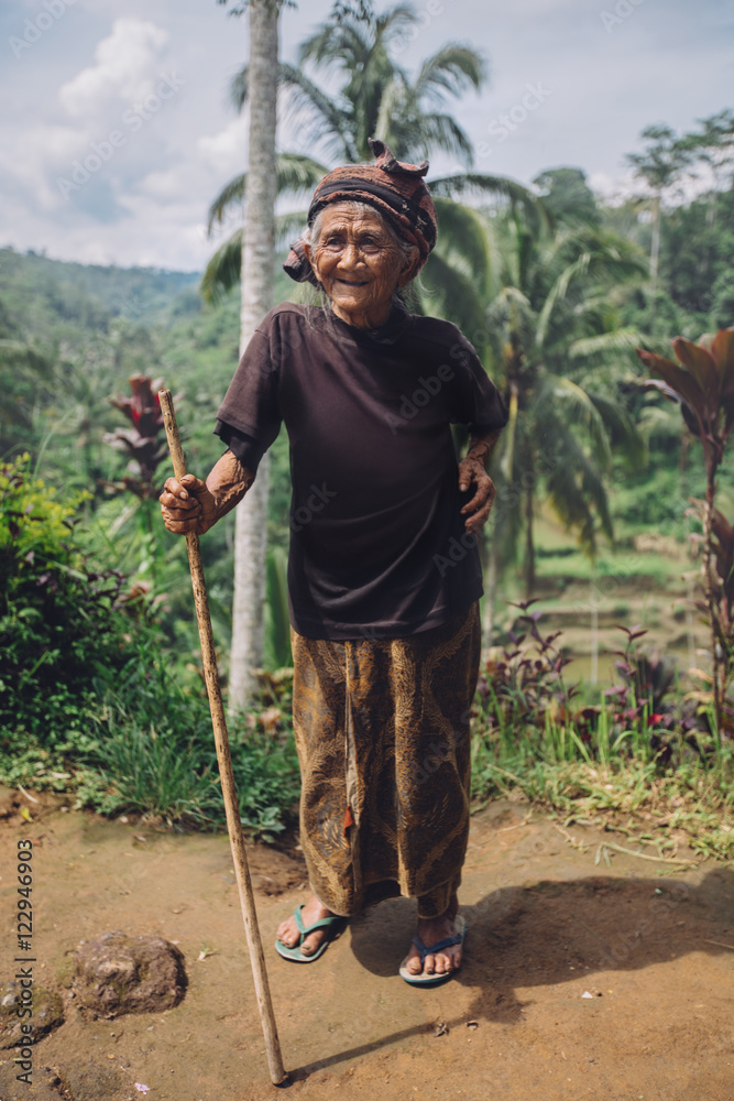 Smiling old woman standing with a stick