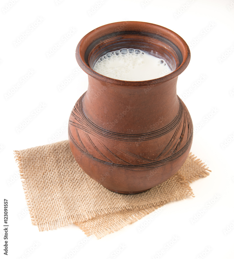 Rustic milk in a clay mug and clover flowers isolated on white background