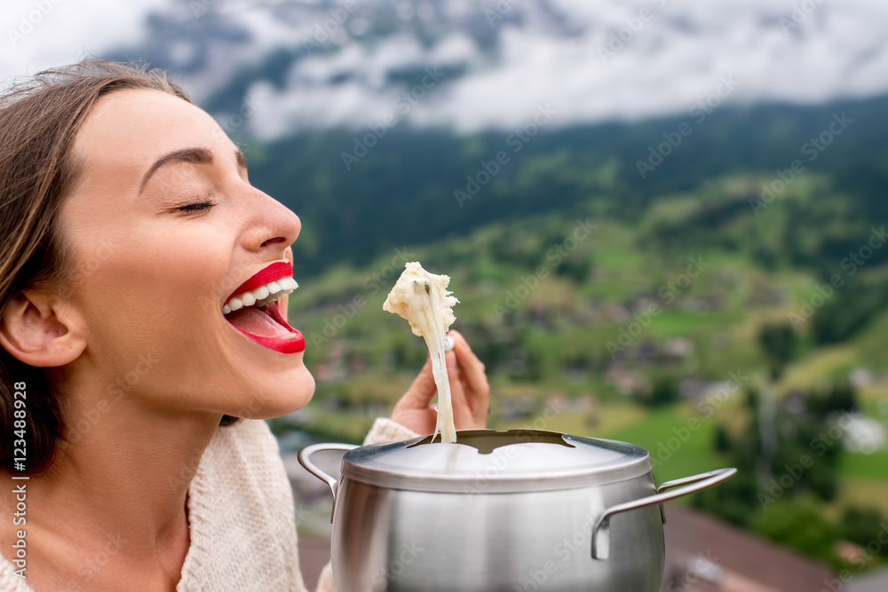 一名年轻女子在瑞士山区旅行时吃火锅，这是一顿传统的瑞士大餐