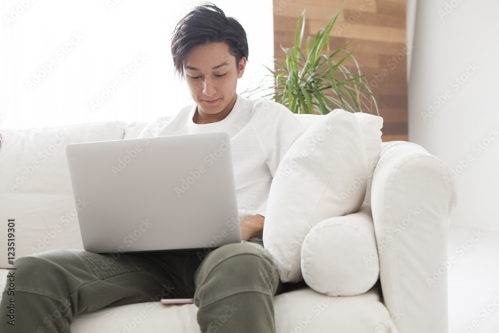 The man is looking at a laptop in the living room