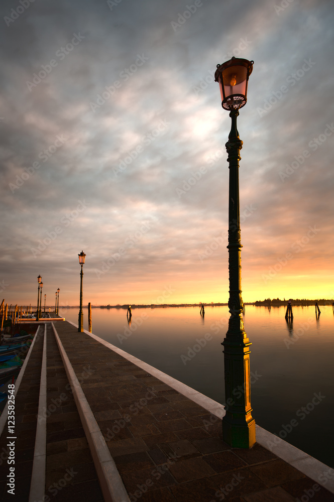 Lamp post by water at sunset