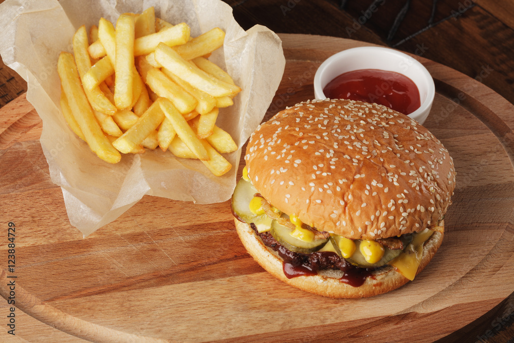 Burger (hamburger) with french fries and sauce. Wooden background.