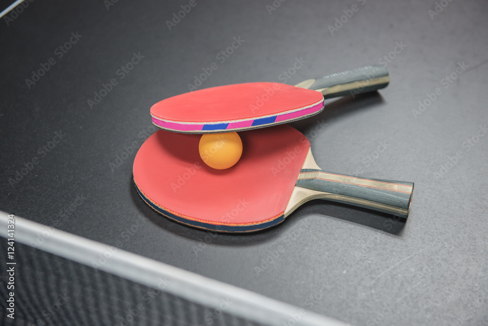 table tennis racket with orange ball on black