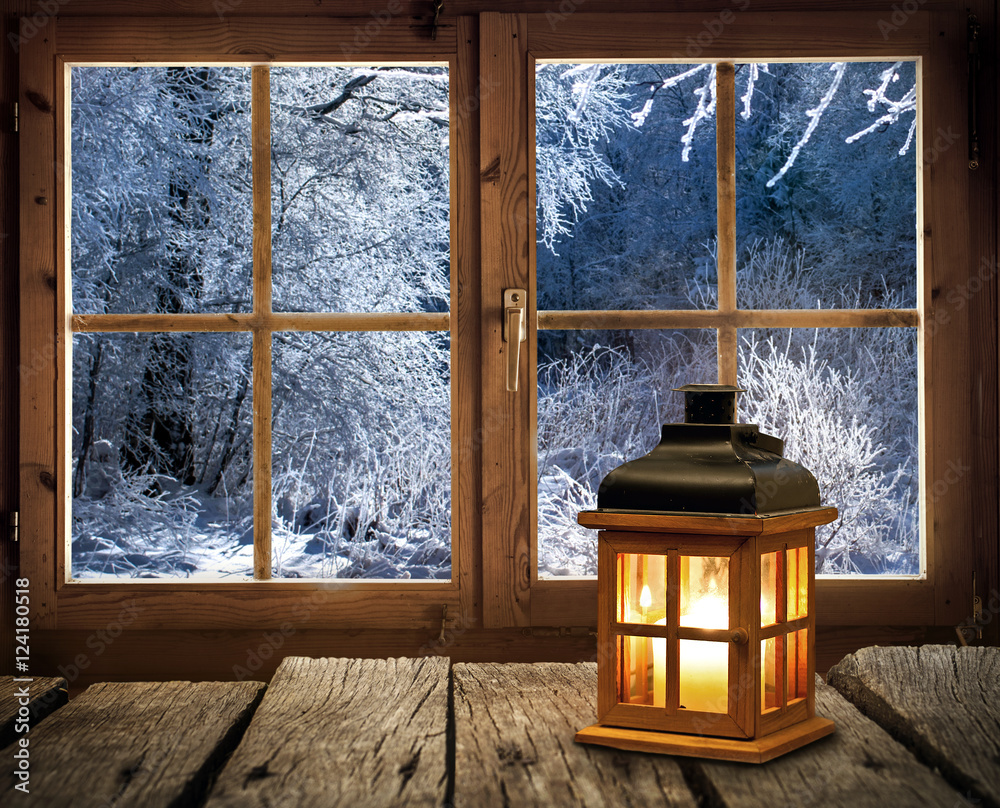 Weihnachten - Laterne vor dem Fenster einer Holzhütte in verschneitem Winterwald