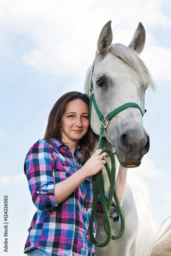 Beautiful young woman with her lovely white horse