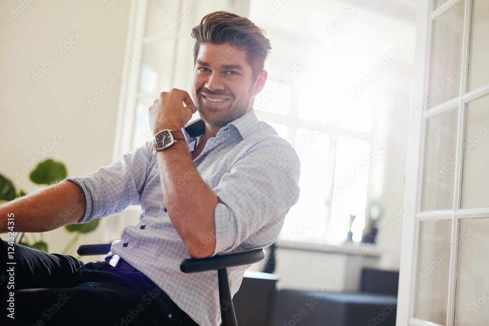 Handsome young man sitting at home and smiling