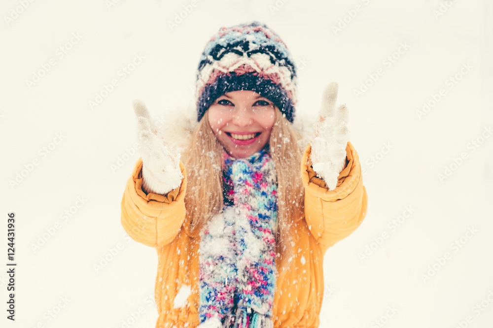 戴着帽子和围巾的年轻女子开心地微笑着在户外玩雪，享受寒假李