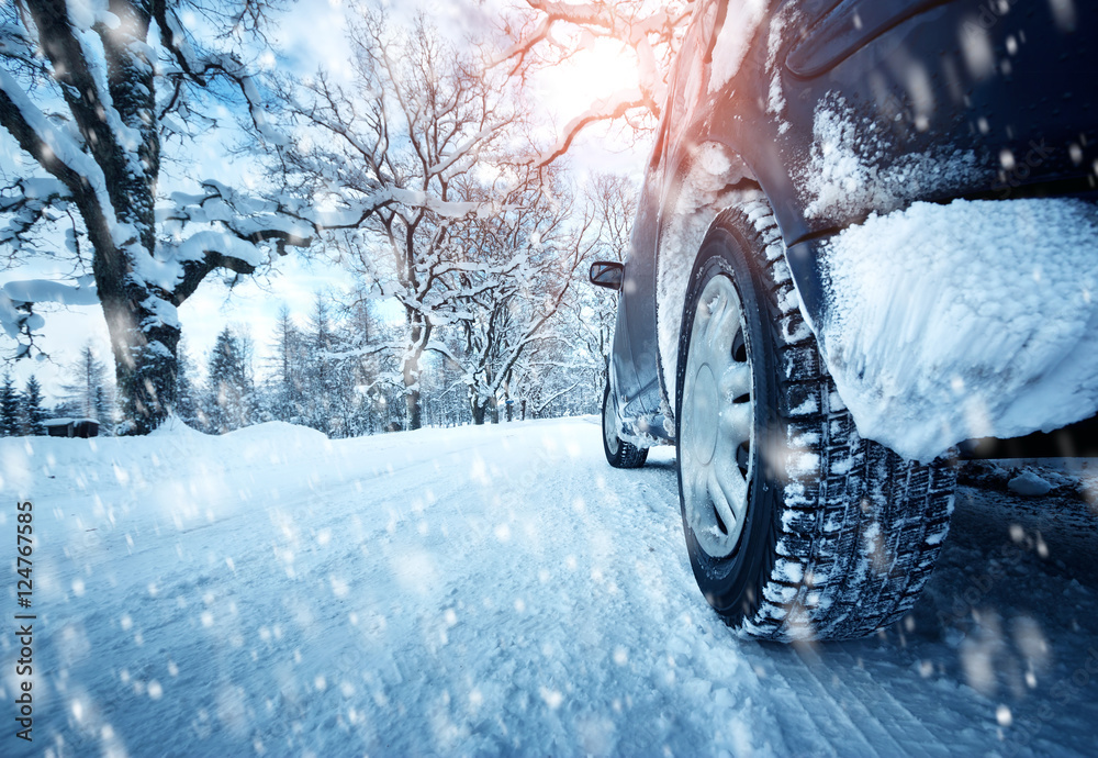 冬季道路上的汽车轮胎被雪覆盖。早上下雪时，车辆在雪地小巷上行驶