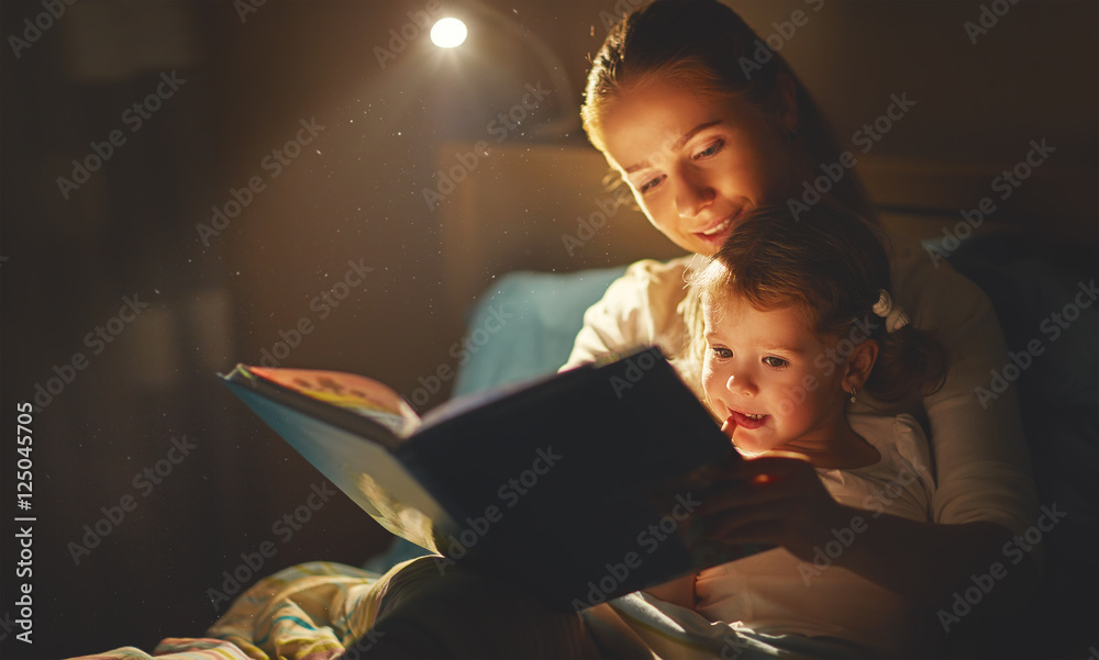 mother and child girl reading a book in bed