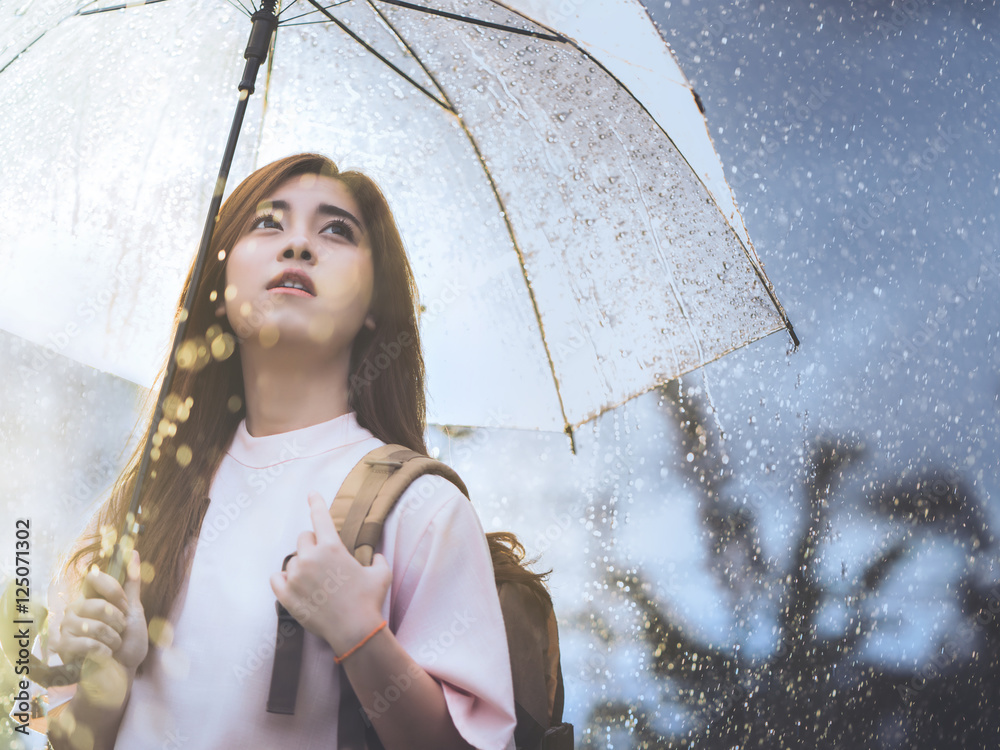 亚洲女人在等雨，她有一把伞。