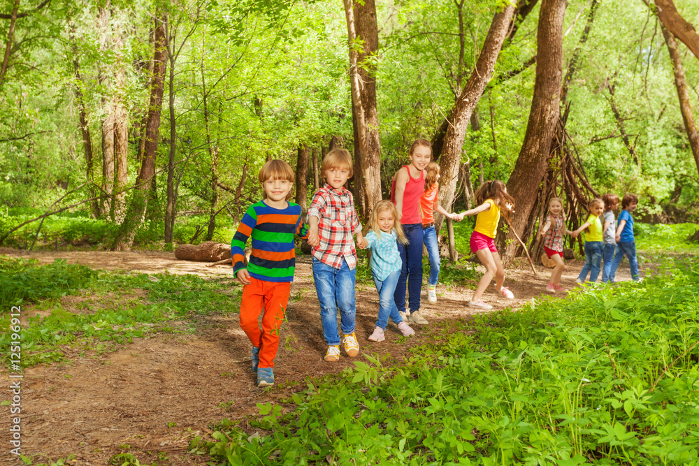 Happy kids walking together holding hands in park