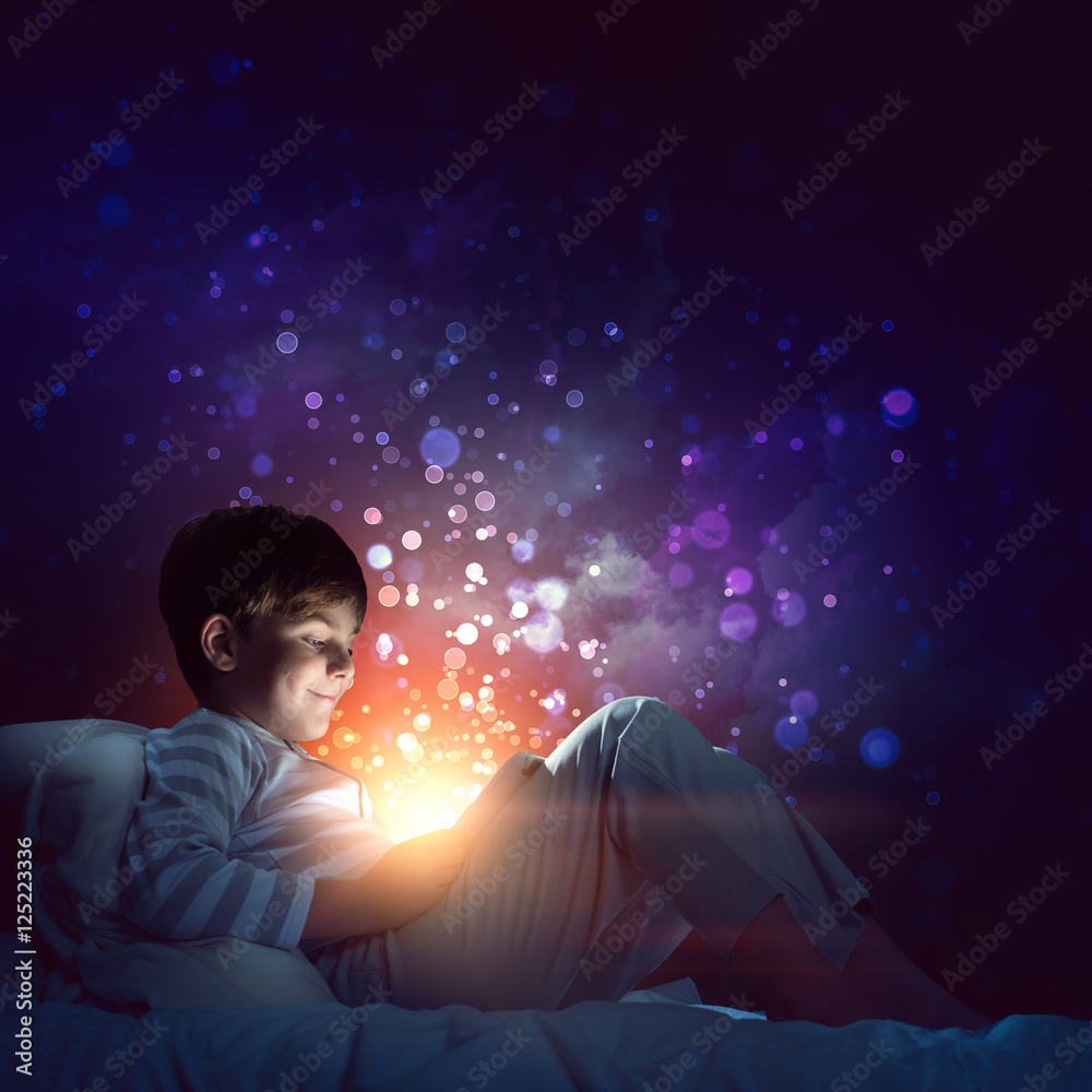 Boy with tablet in his bed