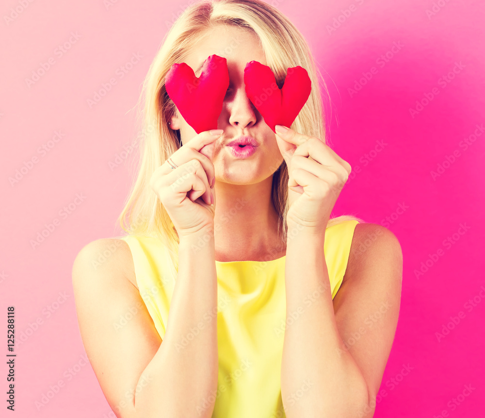 Happy young woman holding heart cushions