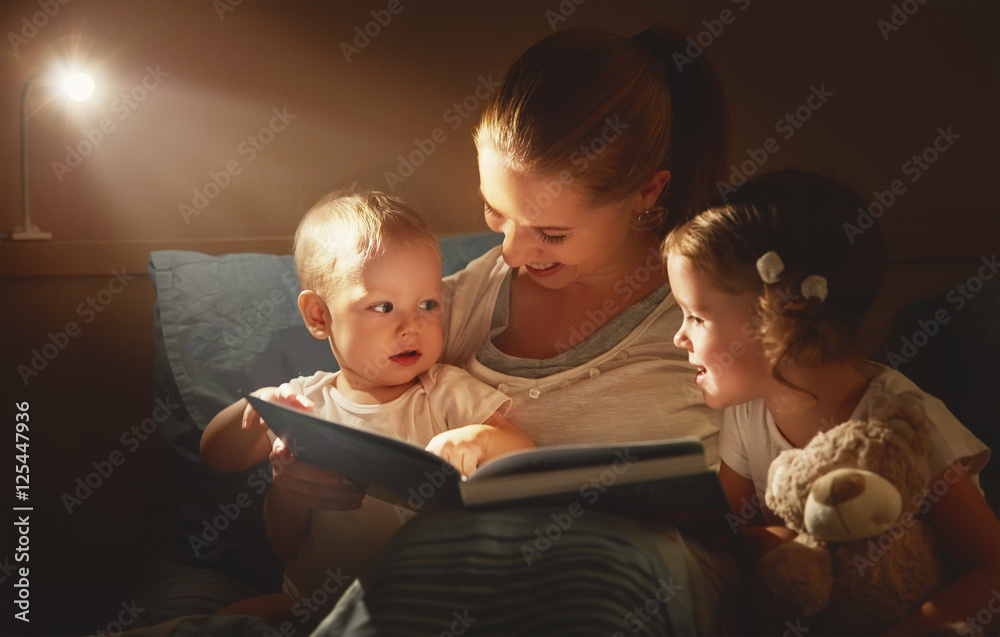 happy family mother and children read a book in bed