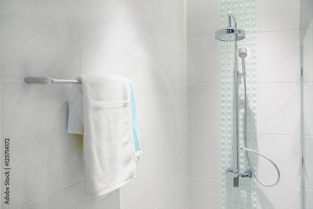 Interior of bathroom with modern shower head and white towel.