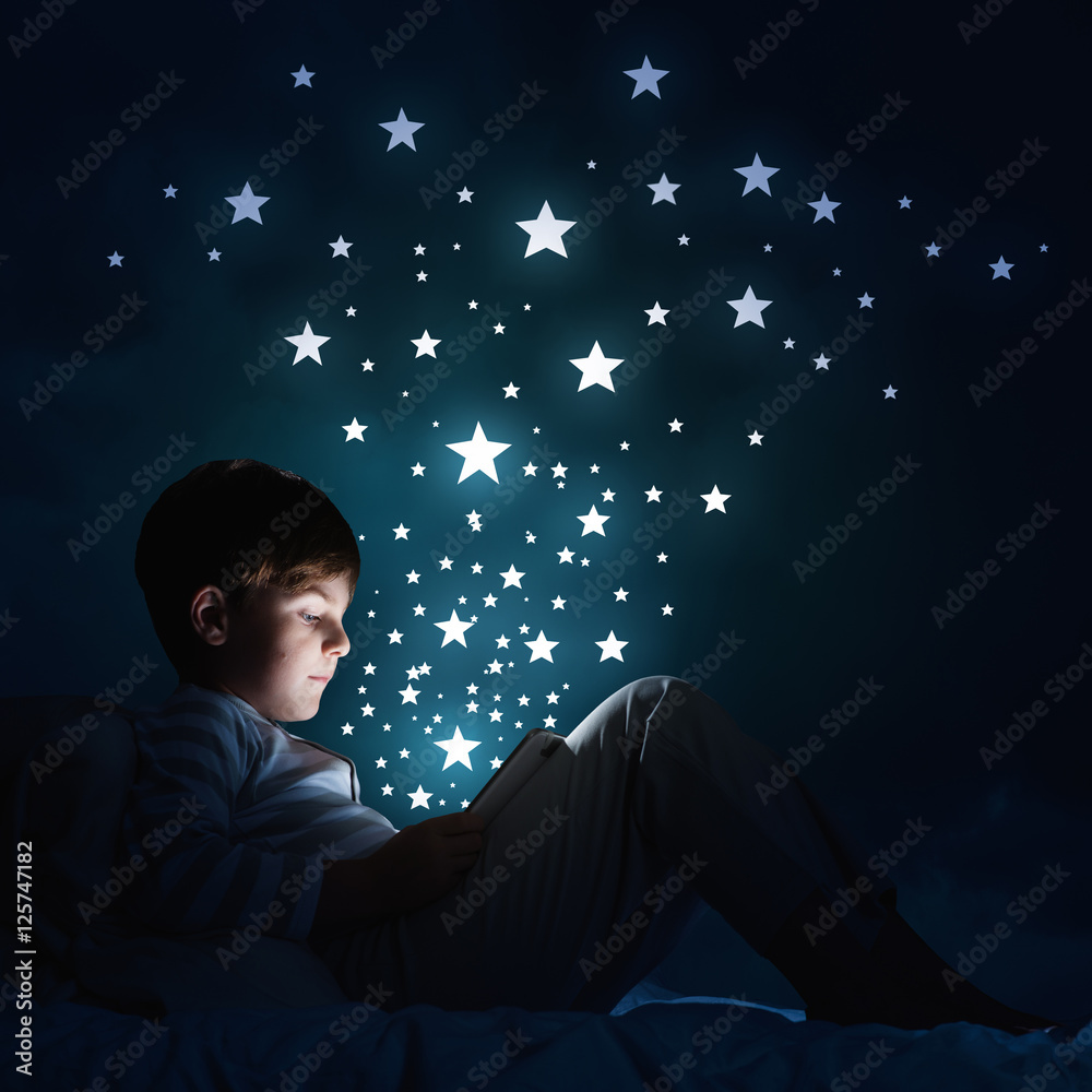 Boy with tablet in his bed