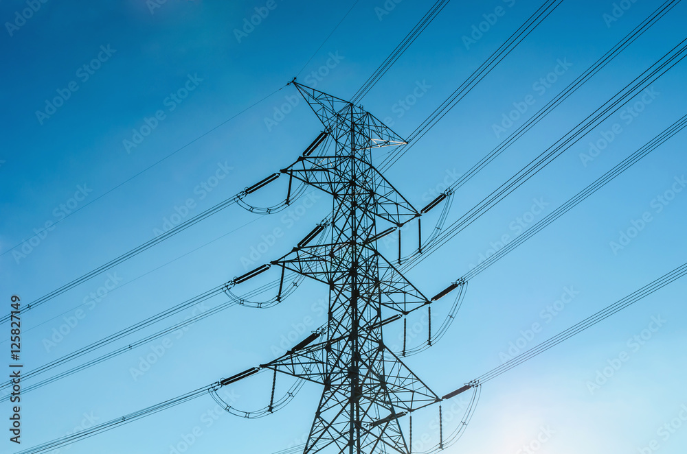 electricity transmission pylon silhouetted against blue sky and sunset